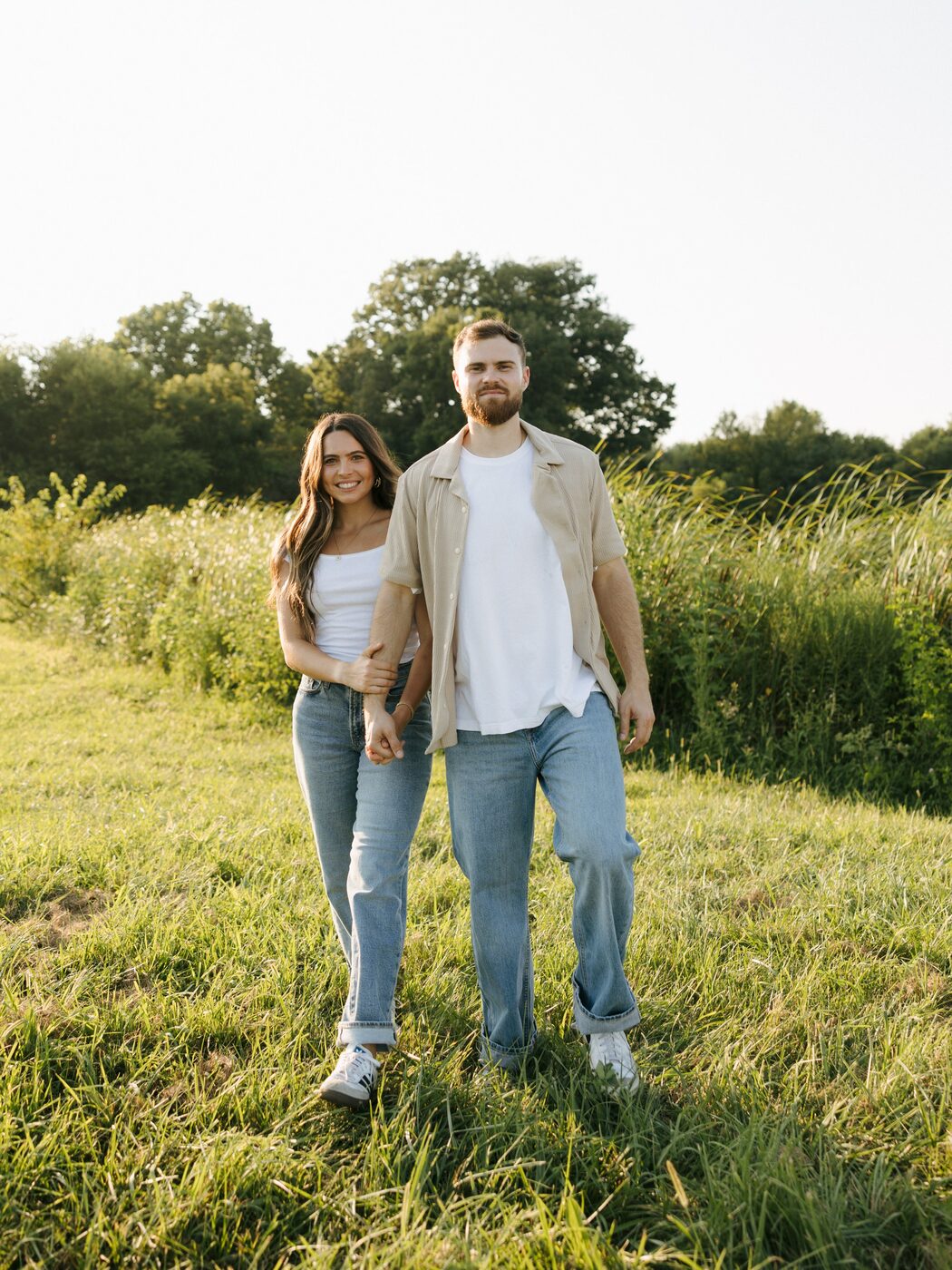 Cade Grubbs, founder of Wood and Wire Home Solutions, walking with his wife through a sunlit field